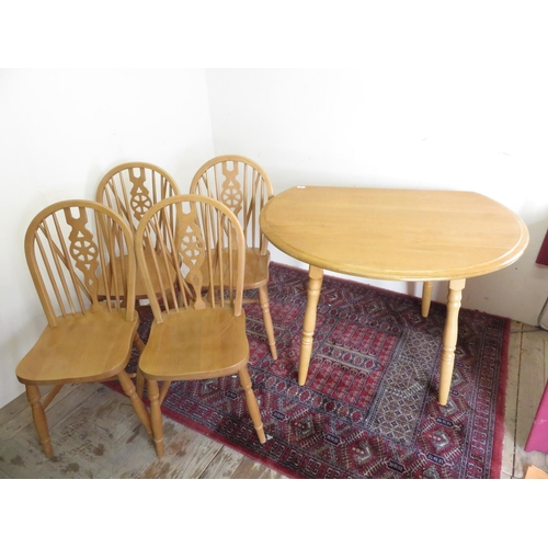 180 - Modern light wood drop-leaf circular table on turned supports, and a set of wheel back dining chairs