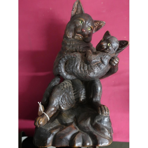 411 - Terracotta model of a seated cat holding a kitten, on rocky base, H40cm