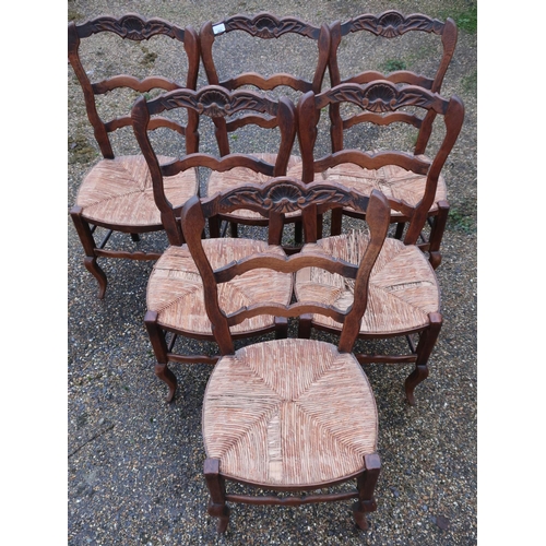 232 - Set of six French oak ladderback rush seated dining chairs, the top rail with carved shell detail