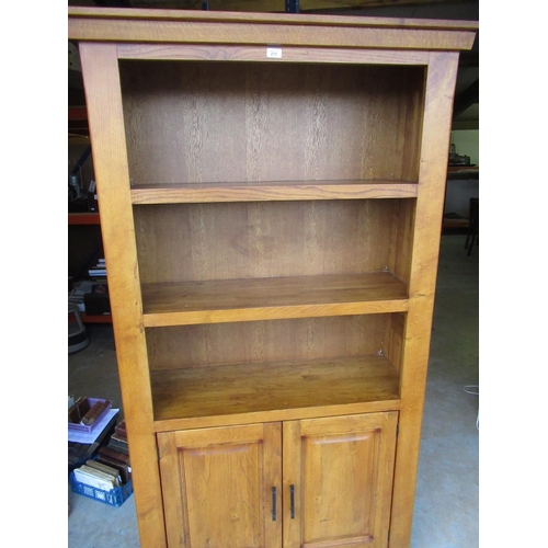 271 - Oak finish bookcase with two shelves above a pair of fielded panelled doors W110cm H190cm D40cm