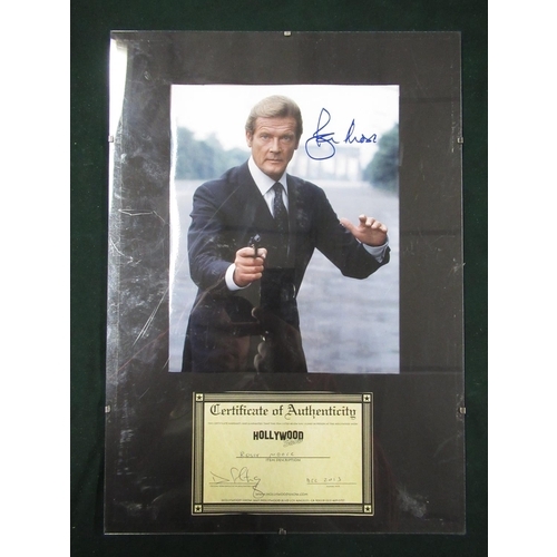 206 - Mounted photograph of Roger Moore as James Bond, signed by Roger Moore with COA, 42cm x 30cm