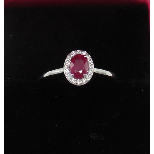 84 - 18ct white gold ring set with oval ruby surrounded by small diamonds (approx. 60 points)