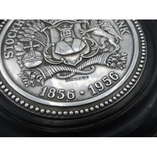 1074 - Stockholms Enskilda Bank 1856-1956 Centenary silver medallion set in a circular ebonised wood paperw... 