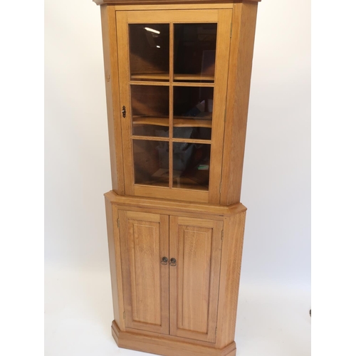 1062 - Andrew Conning Butterfly Furniture - an oak standing corner cabinet with glazed upper door, carved w... 