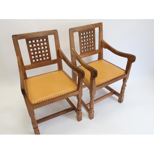 1000 - Robert Mouseman Thompson - a pair of oak elbow chairs with lattice carved backs and brass nail uphol... 