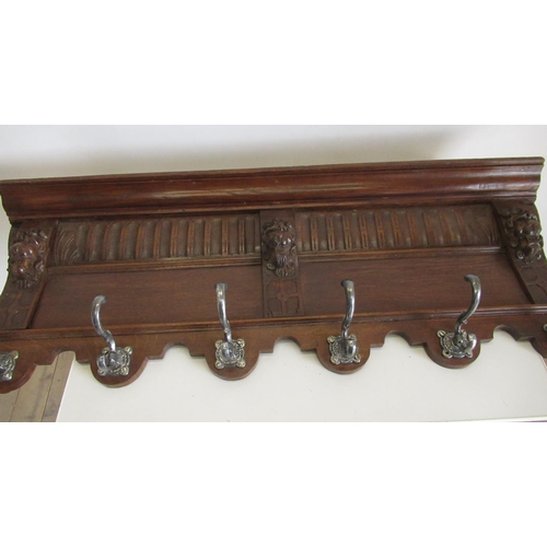 394 - Oak coat rack with arcaded frieze carved with lion mask above six scroll hooks W110cm H39cm