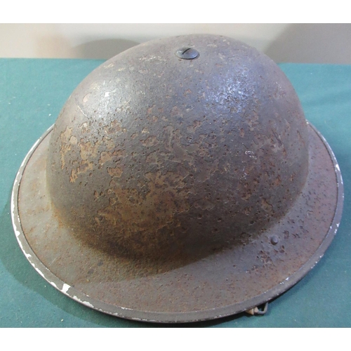 51 - British army issue steel helmets stamped 1/1940 with liner and strap, with remnants of camo netting