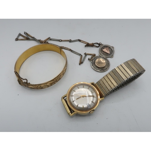 311 - A gold cured hinged gate bracelet with bright cut decoration, two silver fobs, one on chain and a ti... 
