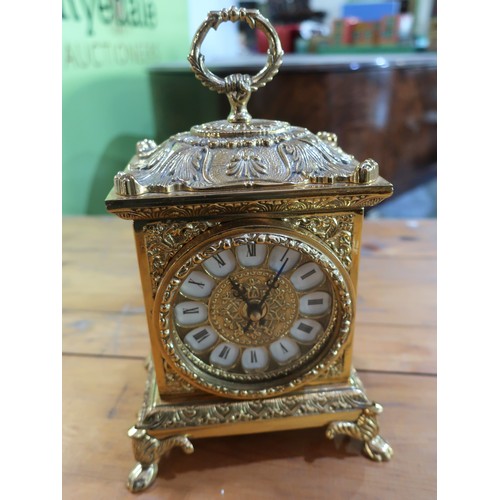 688 - Cast gilt metal mantel clock, cartouche dial and carry loop on four paw feet H24cm