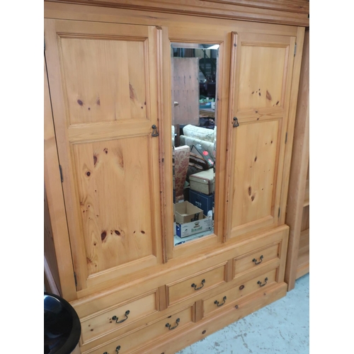 712 - Waxed pine wardrobe with central mirror enclosed by a pair of paneled doors, above three short and t... 