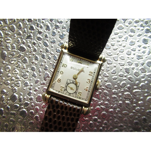 113 - 1940's Bulova hand wound wristwatch. Square 10K rolled gold case with teardrop style lugs on brown l... 