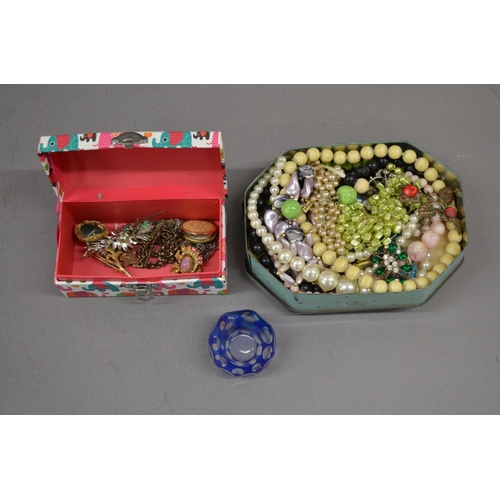 589 - Metal tin and small cardboard box with costume jewellery and a glass paper weight