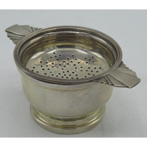 112 - Geo.V Art Deco hallmarked Sterling silver tea strainer and stand with geometric handles and stepped ... 