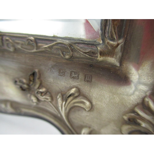 156 - Geo.V mirror with hallmarked Sterling silver repoussé decorated front and easel back (makers marks u... 