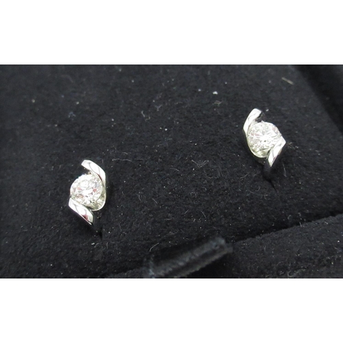 1131 - Pair of diamond stud earrings with round cut diamonds suspended in white metal mounts, 0.15ct clarit... 