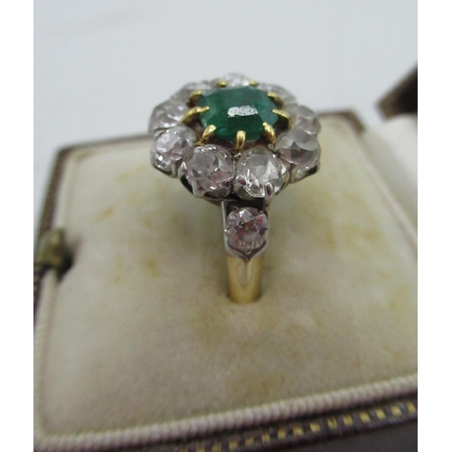 1128 - Diamond and emerald cluster ring with central cushion cut emerald, a halo of ten round cut diamonds ... 