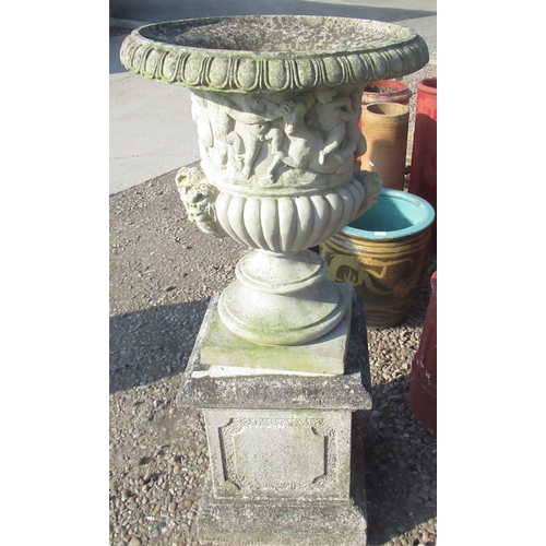 6 - Large composite urn on plinth depicting playing cherubs and four masks approx H48
