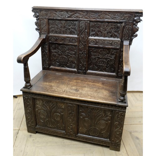 1563 - C20th oak settle, raised scroll work back with four carved panels, moulded down scroll arms and hing... 