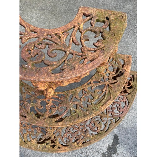 1596 - Cast iron demi-lune plant stand, three pierced graduated tiers on mask head and paw supports, W117cm... 