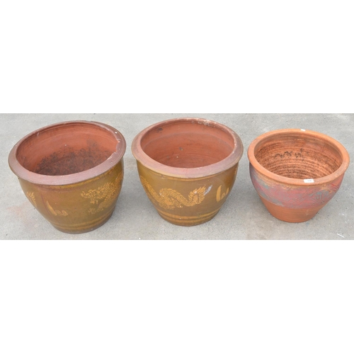176 - Three large painted terracotta pots, two with dragon motif and one floral design (3)