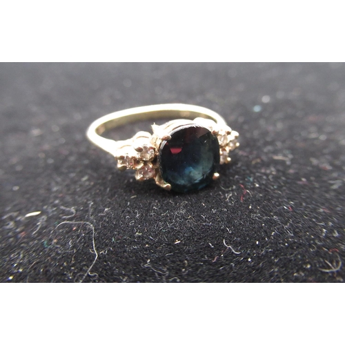 7 - 14ct gold diamond and blue stone ring with an oval cut, claw set faceted blue stone flanked by three... 