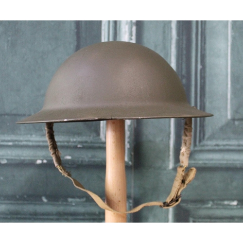 100 - WWII British brodie helmet with paintwork and inner liner, with camouflage netting