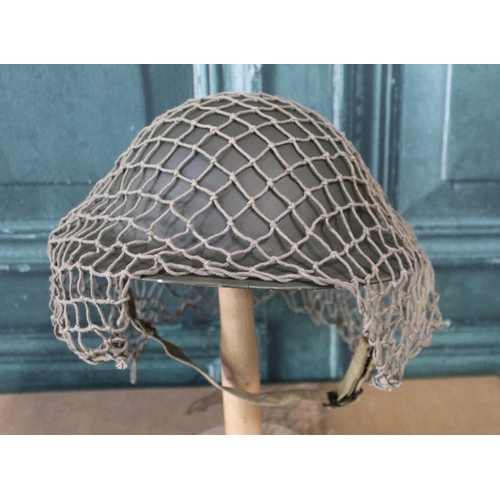 100 - WWII British brodie helmet with paintwork and inner liner, with camouflage netting