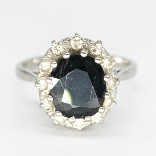 1105 - 18ct white gold sapphire and diamond ring, faceted oval sapphire surrounded by a halo of inset round... 