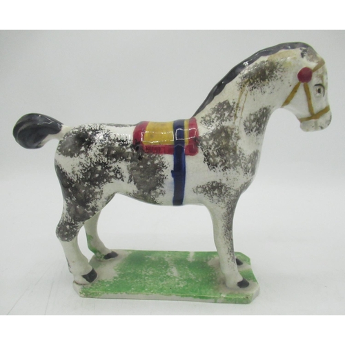 1131 - Prattware model of a horse, sponge decorated with black, blue ocre and red saddle and tack. on shape... 