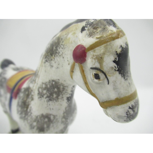 1131 - Prattware model of a horse, sponge decorated with black, blue ocre and red saddle and tack. on shape... 