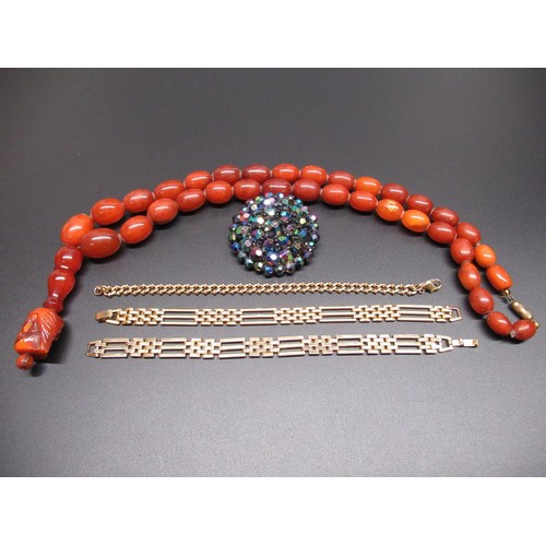 4 - Amber graduated bead necklace with a resin tribal head pendant, a costume jewellery brooch and three... 