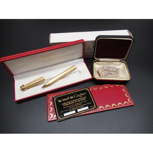 40 - Les Must de Cartier cased ball point pen, boxed with authenticity card, and a pearl necklace with 9c... 