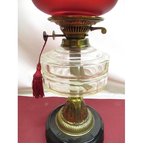 314 - Early C20th oil lamp with cranberry etched shade, clear glass reservoir, on embossed brass base, ter... 