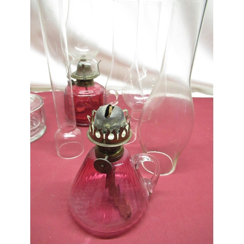 320 - Late C19th handheld oil lamp with cranberry tinted reservoir, H28cm, similar handheld lamp lacking s... 