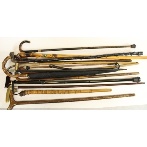 572 - Selection of walking sticks, canes and an umbrella in cylindrical oak umbrella stand