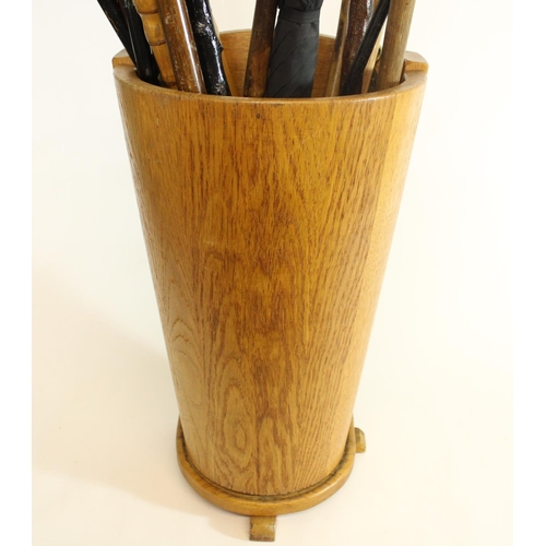 572 - Selection of walking sticks, canes and an umbrella in cylindrical oak umbrella stand