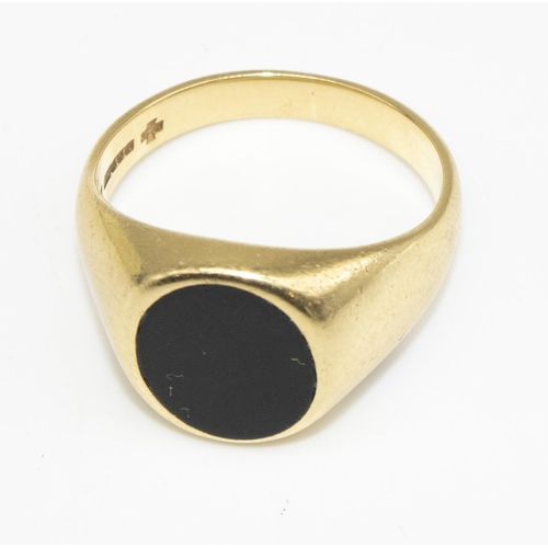 24 - 18ct yellow gold signet ring, the oval face set with a black stone, stamped 750, size R, 10.8g