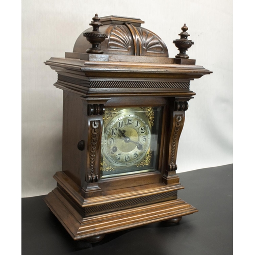 395 - Junghans early C20th walnut cased mantel clock, carved caddy top with turned finial over carved frie... 