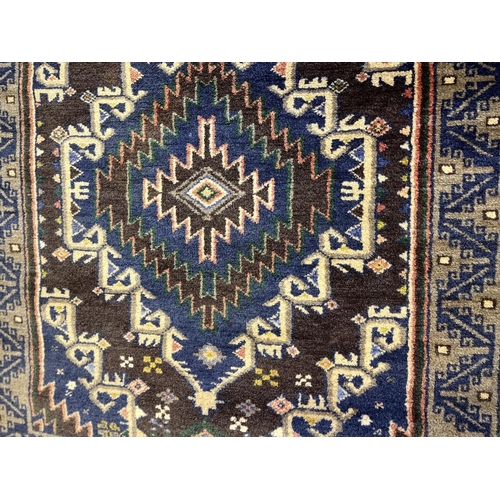 434 - C20th Caucasian pattern wool rug, blue and brown ground, central field set with two stylised geometr... 