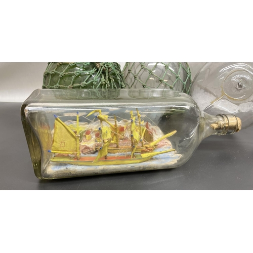 Two green and two clear glass fishing floats, a two masted and a three  masted ship in bottle, and a