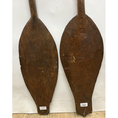 1063 - Two African carved hardwood paddles, L124cm (2)