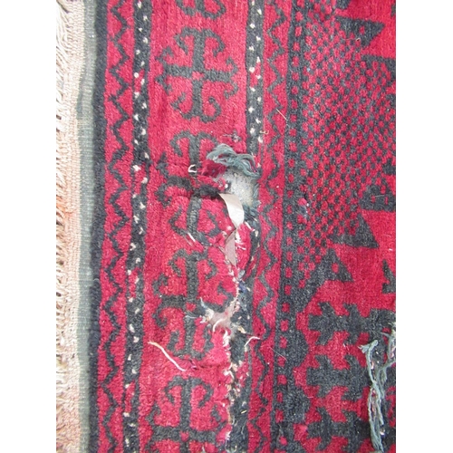 855 - Large Afghan red ground rug, allover decorated with geometric medallions, 400cm x 205cm (A/F)