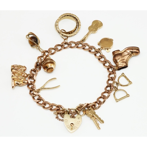 15 - 9ct yellow gold charm bracelet with heart padlock clasp, stamped 375, with charms including stirrups... 