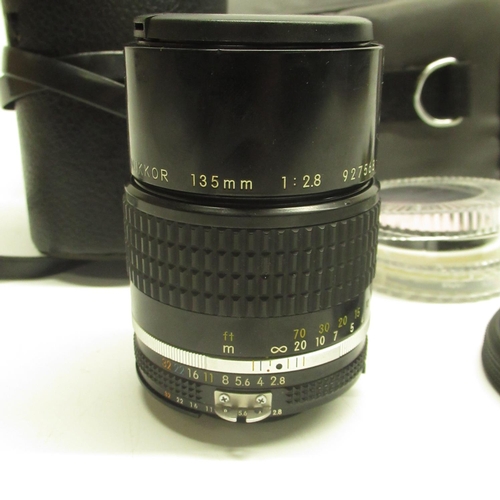 553 - Nikon Nikkor 135mm 1:28 lens with individual black case, lens parts and a grey carry case