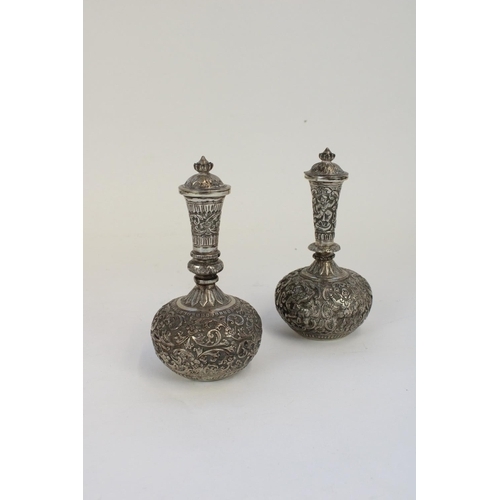 1329 - Near pair of Indian white metal covered vases, heavily embossed with dancing masked figures and foli... 