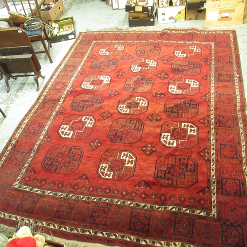 324 - Caucasian pattern rust ground rug, central field with eighteen octagonal geometric pattern roundels ... 