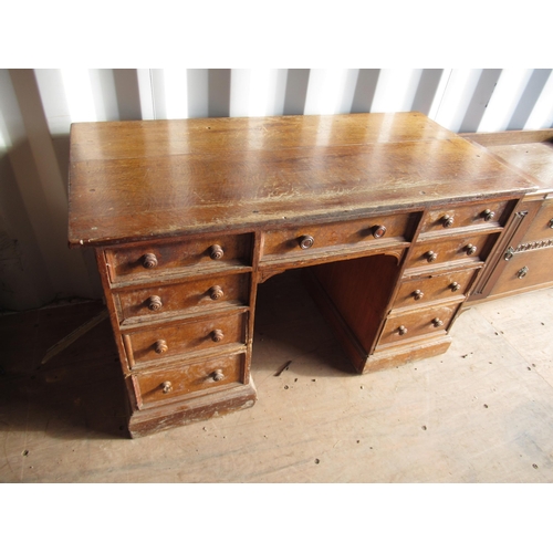 690 - C20th oak twin pedestal desk with nine moulded drawers with turned wooden handles, on skirted base (... 