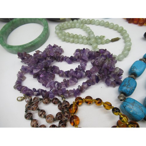42 - Semi precious jewellery including a carved jade bangle, an amethyst necklace, amber beads and a coll... 