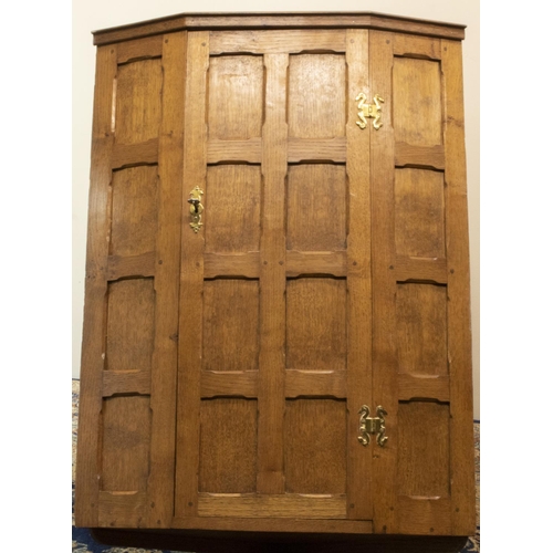 1403 - Yorkshire oak - a panelled oak corner cupboard, door with brass H handles revealing two shelves, W66... 