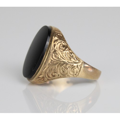 1042 - 9ct yellow gold signet ring, the oval face set with black stone, on scroll detailed shoulders and pl... 
